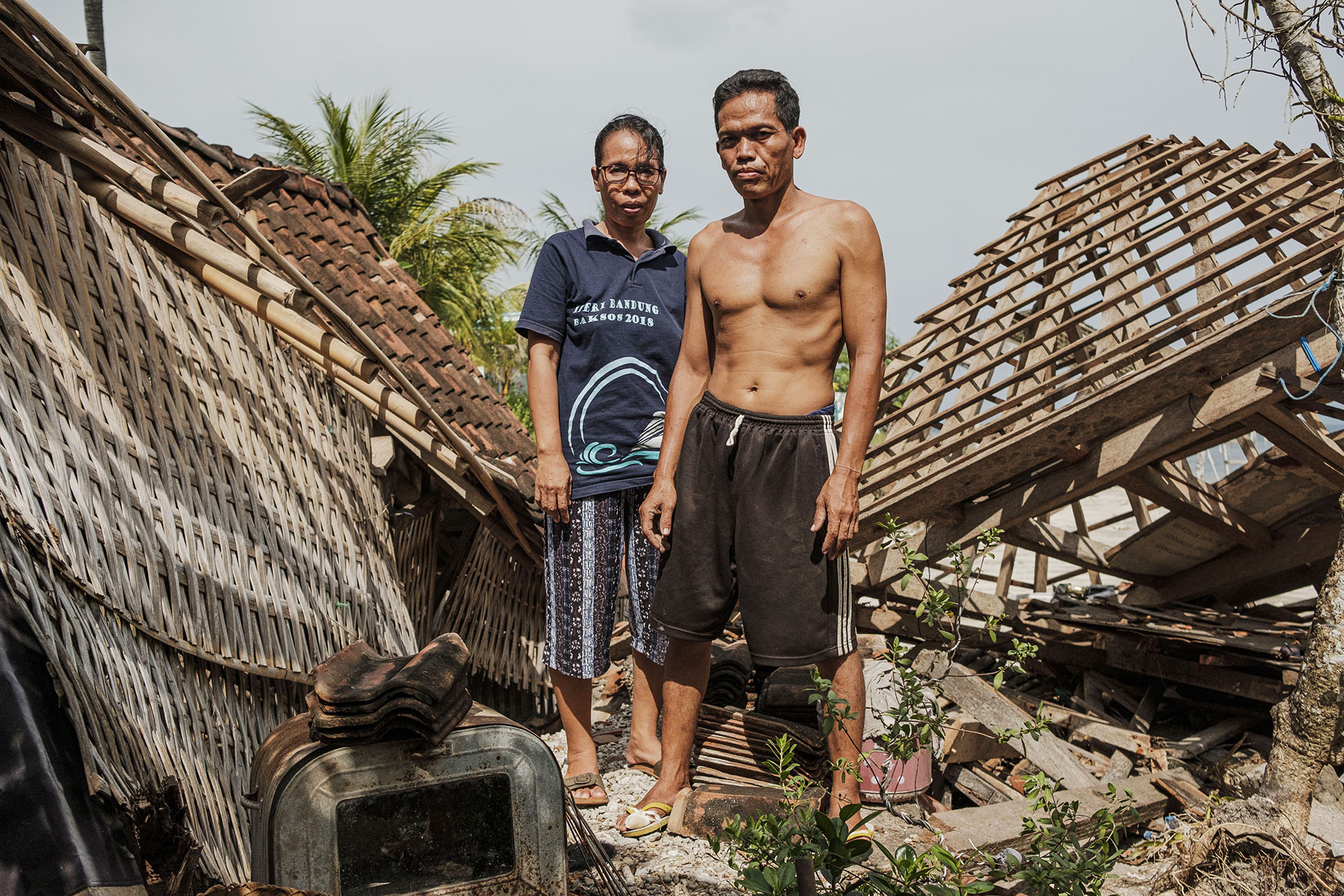 Nyoman Wardana (right) and Desk Antari (left) standing on what is left of their house