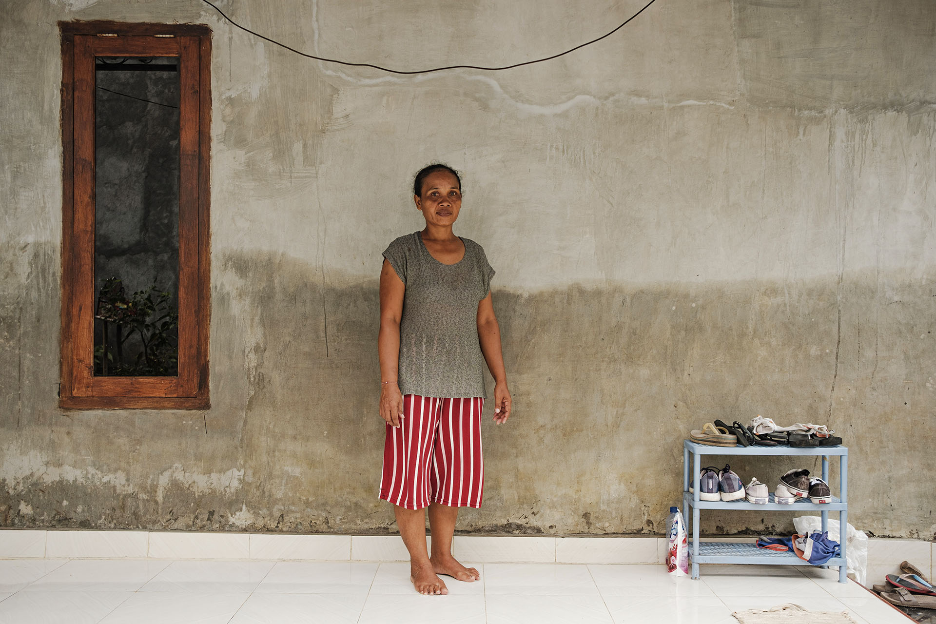 At Komang Sugantini house. The differences of colors of the wall behind her indicate the water level during the flood.