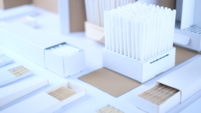 Custom pre-rolled cones neatly arranged in white display packaging boxes on a worktable