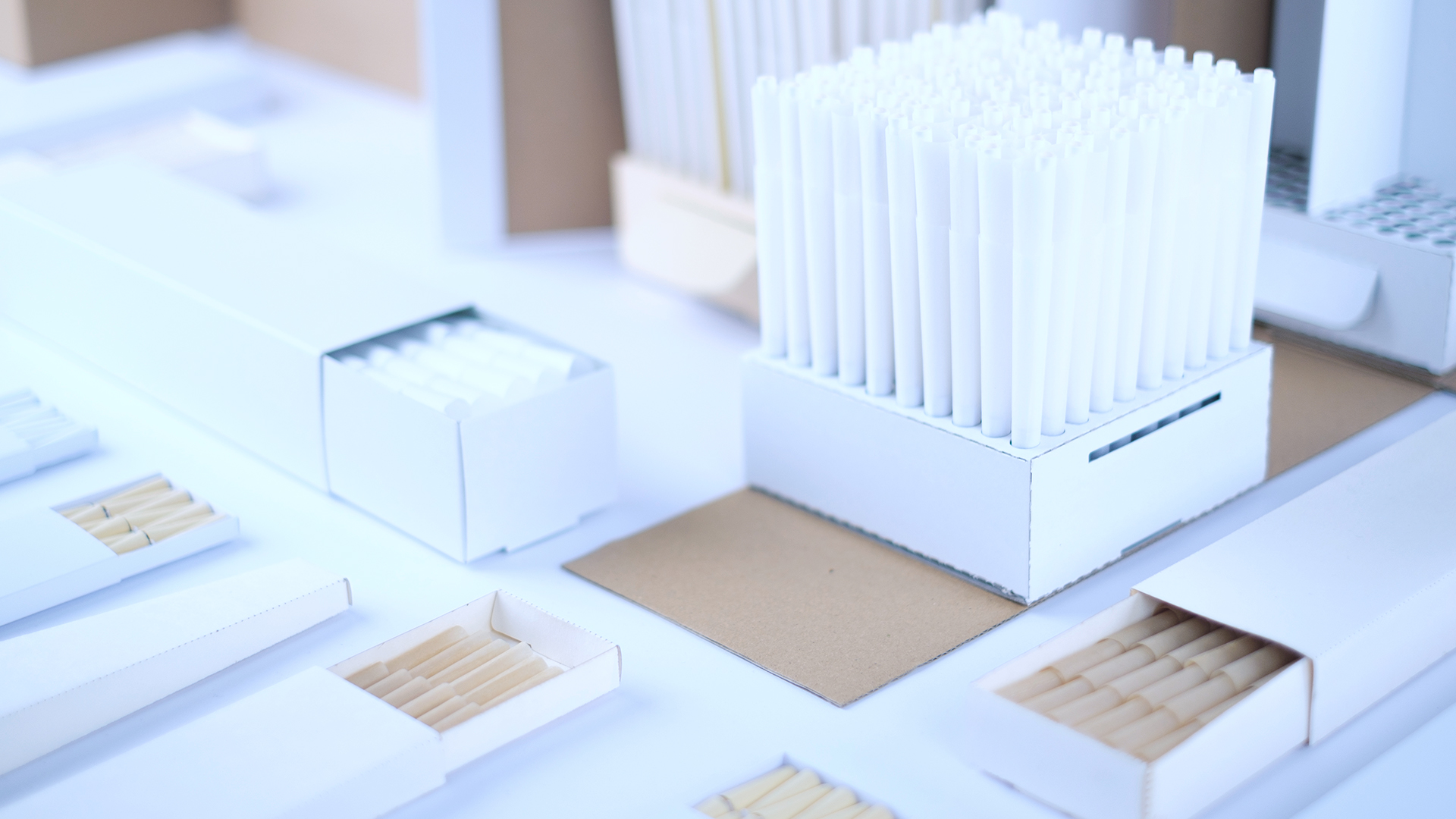 Custom pre-rolled cones neatly arranged in white display packaging boxes on a worktable