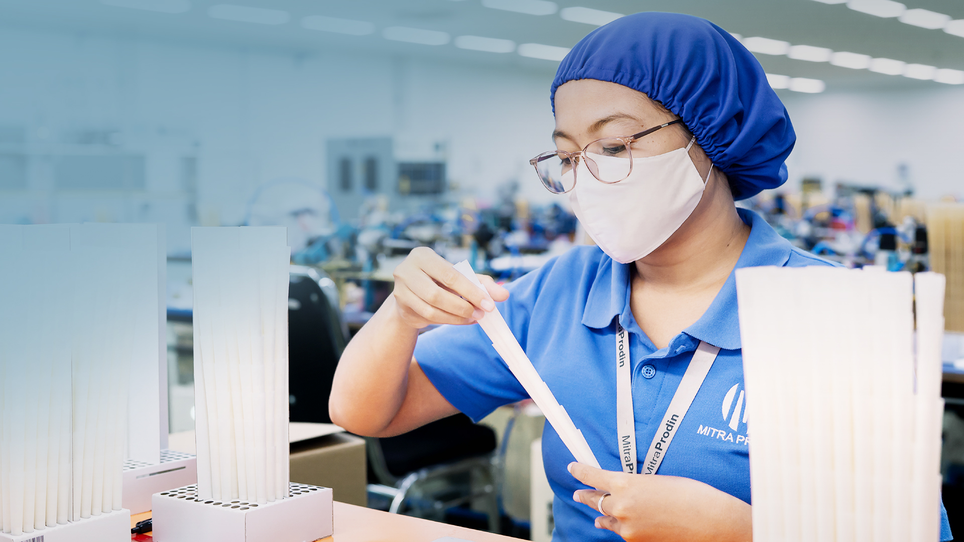 Quality assurance technician examining a paper pre-roll cone in a manufacturing facility.