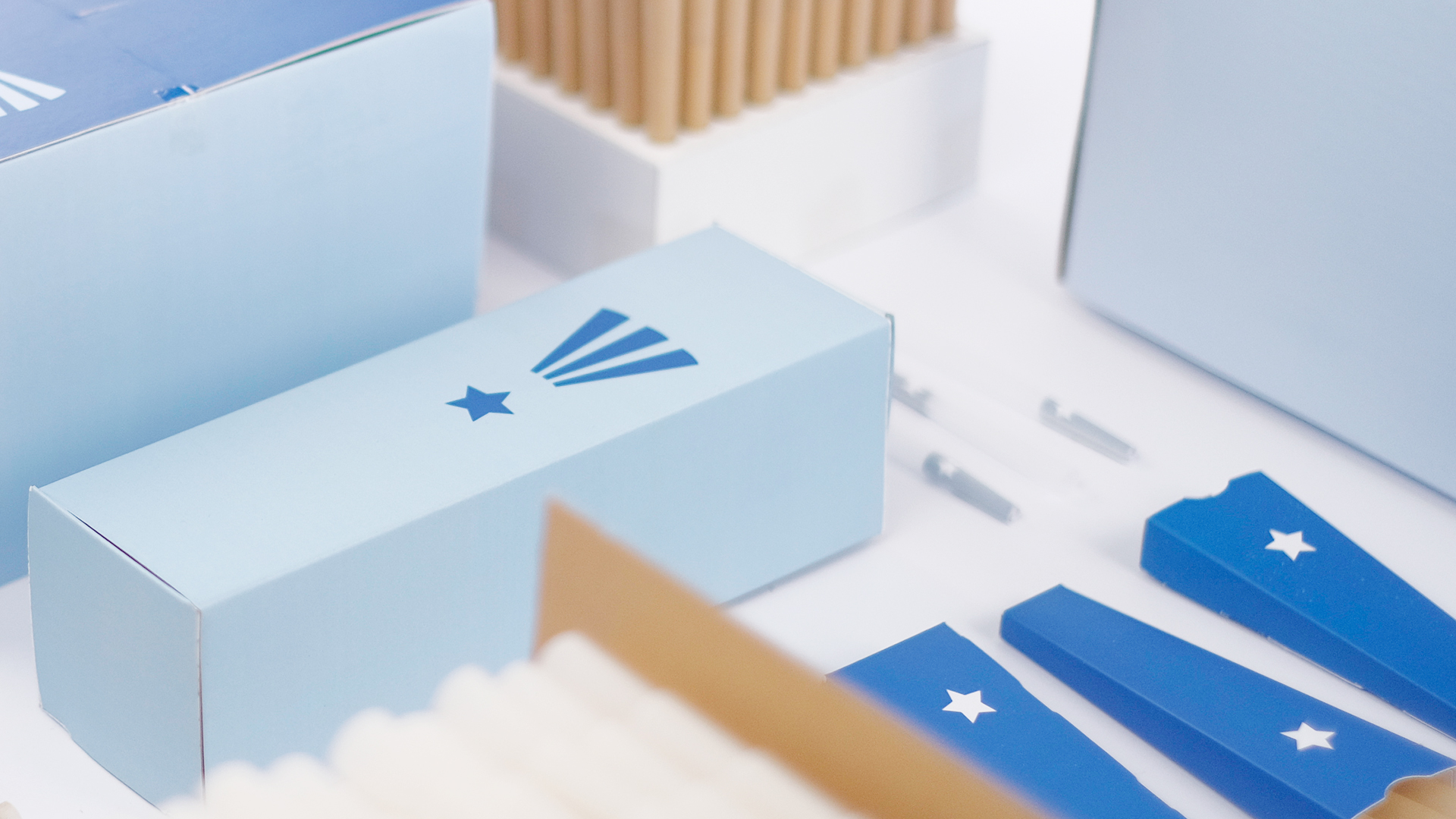 Custom printed light blue packaging box with star logo beside kraft paper filter tips and branded cards